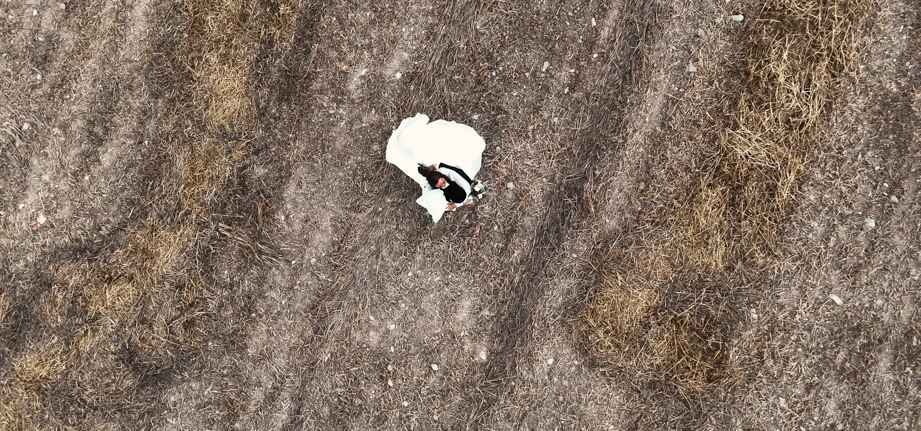 Fotograma de vídeo de boda de DOME Weddings: plano cenital con dron de la novia en mitad de un campo