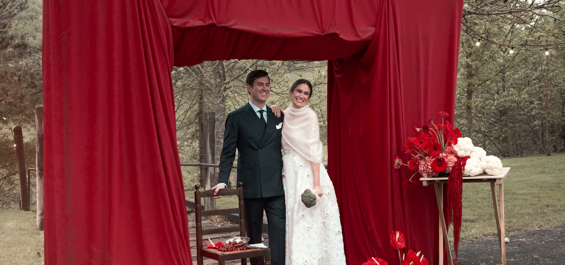 Fotograma de vídeo de boda de DOME Weddings: los novios bajo un cortinaje rojo